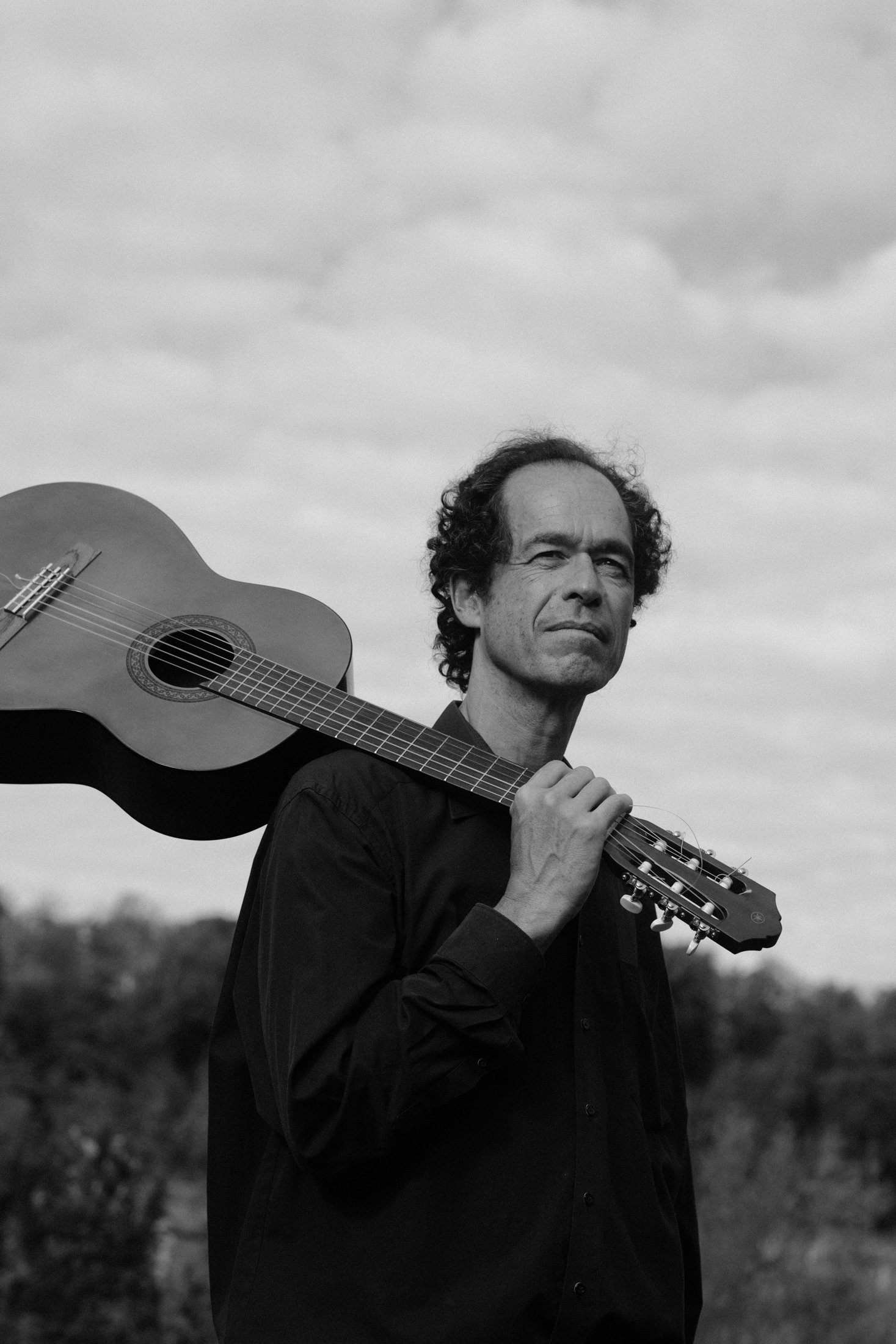 Black-and-white portrait of Jérôme Inen with a classical guitar resting on his shoulder